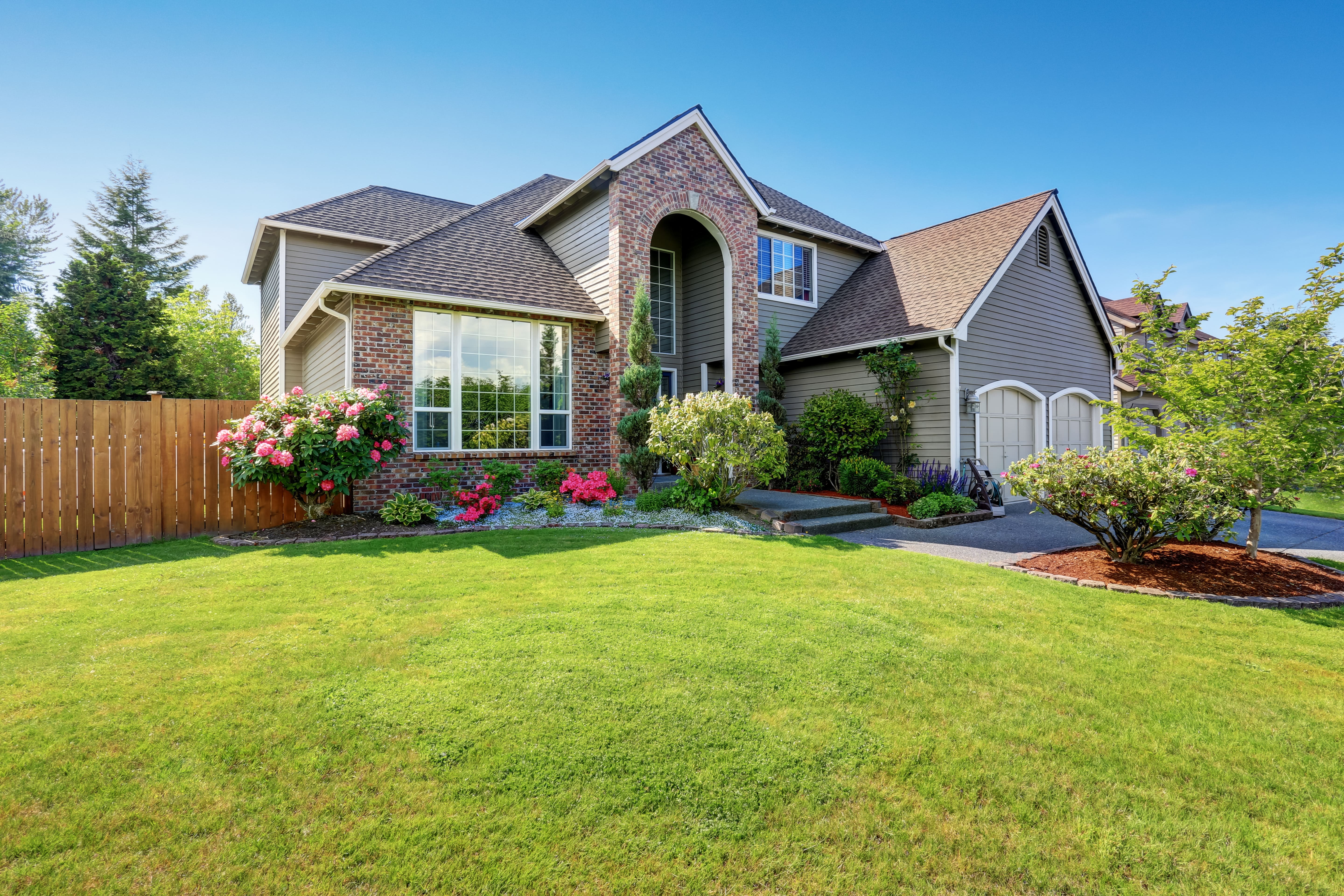 Front of two story brick house with lush yard.